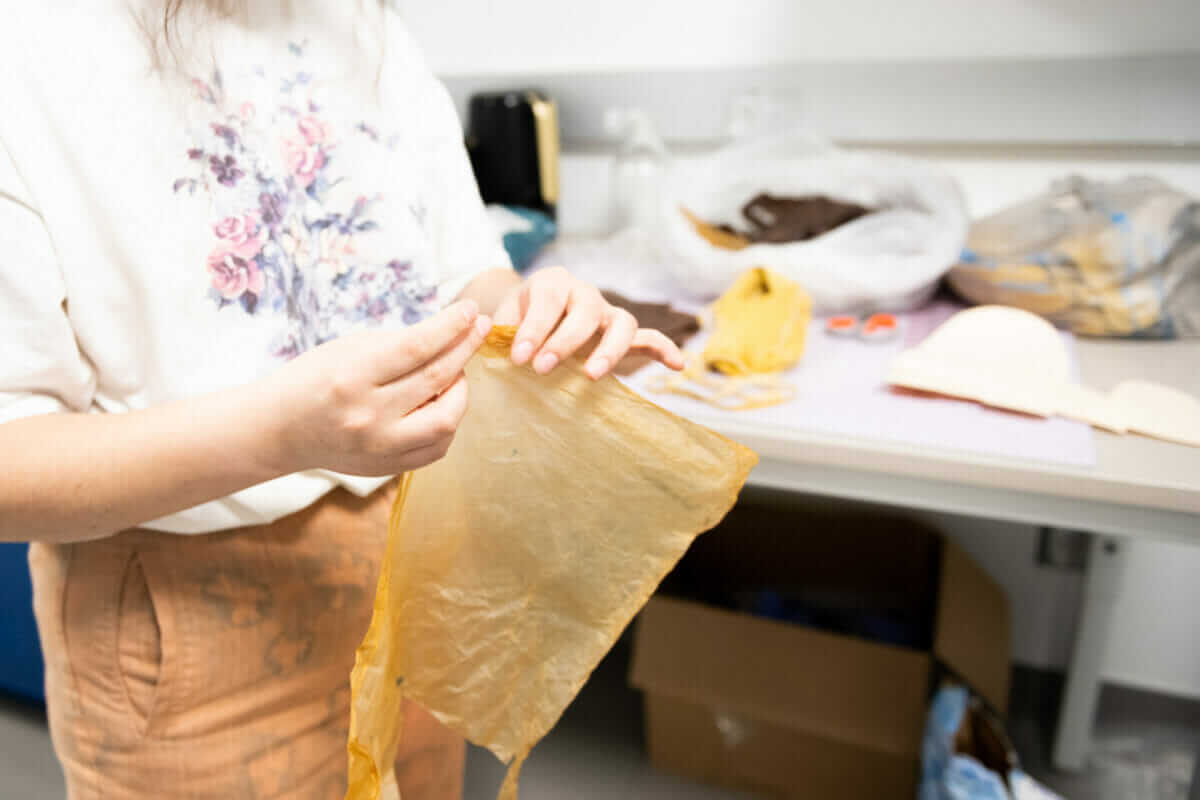 Hands holding textile made from kombucha SCOBY.