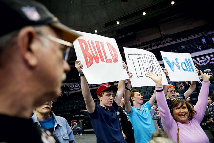 Trump supporters at a 2016 campaign rally in Tampa, FL, hold signs advocating strict border security.