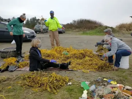 A group of five people on the beach surrounded by yellow rope fragments.