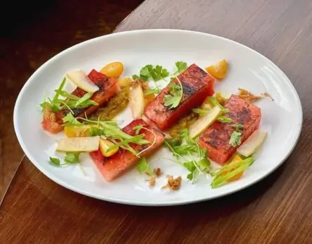 Brûléed Red-n-Sweet heirloom watermelon paired with preserved kumquat, snap peas, watermelon rind amba, formosa, sun tea vinaigrette, celery leaves by Chef Leah Branch at the Roosevelt in Richmond, Virginia.